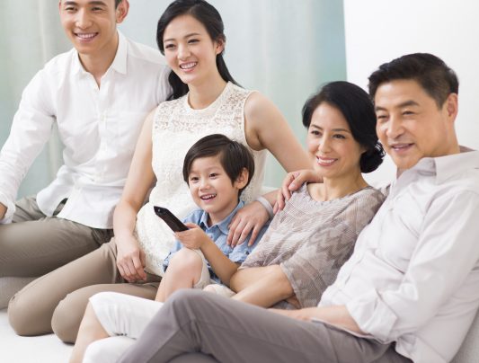 Happy big Chinese family watching TV at home