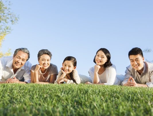 Portrait of Chinese family lying down on the lawn in a park
